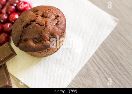 Schoko-Muffin mit Sauerkirschen auf weiße Serviette. Draufsicht mit Textfreiraum Stockfoto