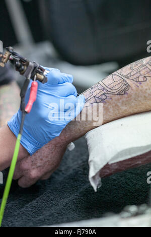 Tattoo-Künstler mit blauen Latex Handschuhen Tätowierungen eine Bio-mechanische Bilder auf Kunden-arm Stockfoto