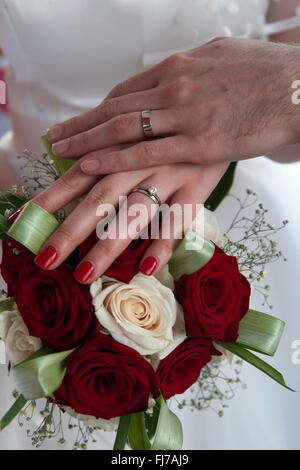 Hochzeitspaare die Hände auf einem Bouquet zeigt ihre Eheringe Stockfoto