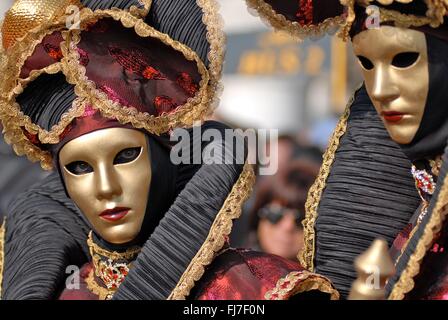 Frauen tragen goldene venezianische Masken und Kostüme während der jährlichen Karneval von Venedig in Venedig, Italien. Karneval läuft offiziell für 10 Tage auf die christliche Feier der Fastenzeit endet. Stockfoto