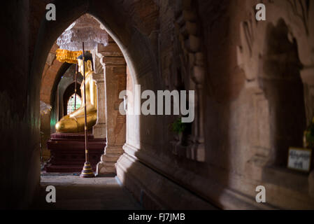 Htilominlo-Tempel Gautama-Buddha-Statue Nyaung-U Myanmar // NYAUNG-U, Myanmar — Eine goldene Statue des Gautama-Buddhas steht im Htilominlo-Tempel, einem der prominenten buddhistischen Tempel in der antiken Stadt Bagan. Der Tempel Htilominlo wurde Anfang des 13. Jahrhunderts während der Regierungszeit von König Htilominlo erbaut und repräsentiert den architektonischen Stil der späten Bagan-Zeit. Der Tempel ist bekannt für seine gut erhaltenen Fresken und mehrere Buddha-Bilder, die in seinen Innenräumen untergebracht sind. Nyaung-U dient als Tor zur archäologischen Zone Bagan, die Tausende von buddhistischen Tempeln beherbergt Stockfoto