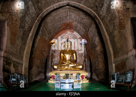 Htilominlo-Tempel Gautama-Buddha-Statue Bagan Myanmar // NYAUNG-U, Myanmar — Eine goldene Statue des Gautama-Buddhas steht im Htilominlo-Tempel, einem der prominenten buddhistischen Tempel in der antiken Stadt Bagan. Der Tempel Htilominlo wurde Anfang des 13. Jahrhunderts während der Regierungszeit von König Htilominlo erbaut und repräsentiert den architektonischen Stil der späten Bagan-Zeit. Der Tempel ist bekannt für seine gut erhaltenen Fresken und mehrere Buddha-Bilder, die in seinen Innenräumen untergebracht sind. Nyaung-U dient als Tor zur archäologischen Zone Bagan, die Tausende von buddhistischen Tempeln, Pagod, enthält Stockfoto
