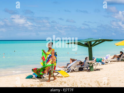 Lokale Frau verkaufen bunte Schals, wraps, Sarongs und Handtücher am Strand in Runaway Bay, nördlich von Antigua, Antigua und Barbuda Stockfoto