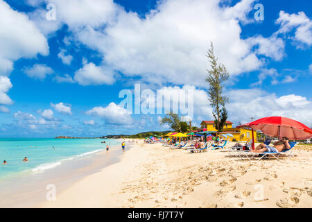 Bunte Sonnenschirme am Strand von Runaway auf Runaway Bay, Dickenson Bay, Antigua, Norden an einem sonnigen Tag mit flauschigen Wolken Stockfoto