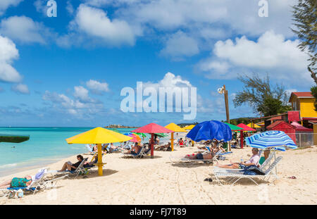 Bunte Sonnenschirme am Strand von Runaway auf Runaway Bay, Dickenson Bay, Antigua, Norden an einem sonnigen Tag mit flauschigen Wolken Stockfoto