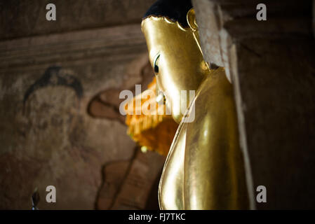 Htilominlo-Tempel Gautama-Buddha-Statue Nyaung-U Myanmar // NYAUNG-U, Myanmar — Eine goldene Statue des Gautama-Buddhas steht im Htilominlo-Tempel, einem der prominenten buddhistischen Tempel in der antiken Stadt Bagan. Der Tempel Htilominlo wurde Anfang des 13. Jahrhunderts während der Regierungszeit von König Htilominlo erbaut und repräsentiert den architektonischen Stil der späten Bagan-Zeit. Der Tempel ist bekannt für seine gut erhaltenen Fresken und mehrere Buddha-Bilder, die in seinen Innenräumen untergebracht sind. Nyaung-U dient als Tor zur archäologischen Zone Bagan, die Tausende von buddhistischen Tempeln beherbergt Stockfoto
