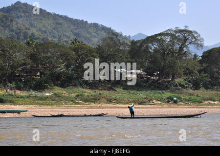 Traditionelle Boote und Fischer, Berge im Hintergrund, Mekong-Fluss, Laos Stockfoto