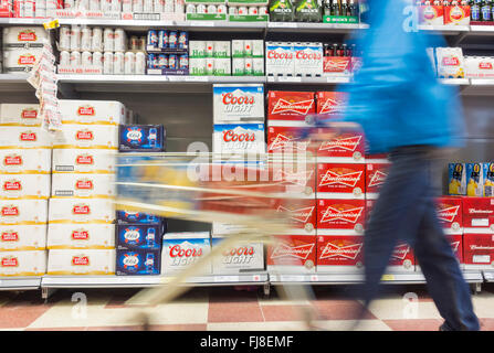 Mann mit Fällen von Bier im Einkaufswagen im Supermarkt. UK Stockfoto