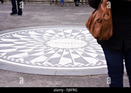 Eine Frau stand auf dem John Lennon vorstellen Denkmal in Strawberry Fields-Abschnitt des New Yorker Central Park Stockfoto