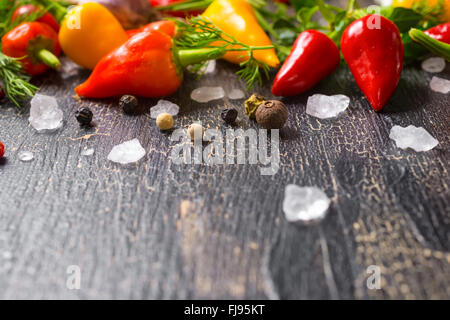 Meersalz, trockene Gewürze, gelb, red hot chilli peppers, verschiedenen grün, auf Risse schwarzer Hintergrund, Nahaufnahme Stockfoto