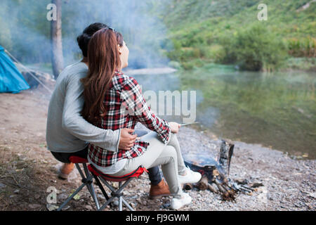 Junge chinesische Paare sitzen neben Lagerfeuer zubereiten Stockfoto