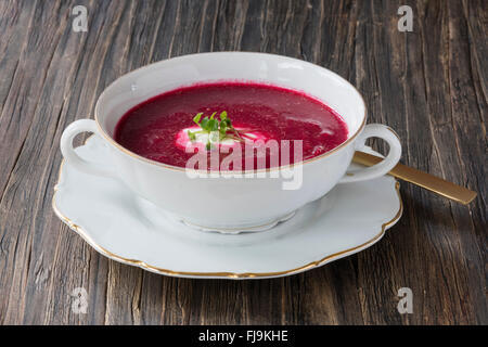 Köstliche Bio rote Bete Suppe in einer weißen Schale auf einer dunklen Holzoberfläche Stockfoto