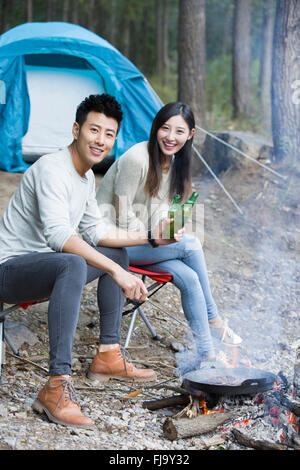 Junge chinesische Paare sitzen neben Lagerfeuer zubereiten Stockfoto