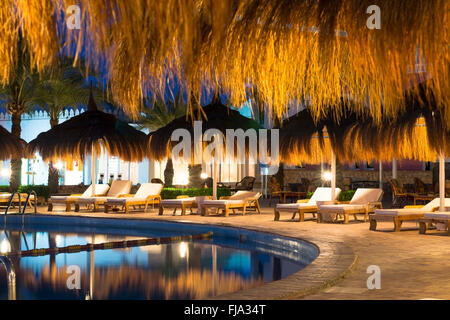 SHARM EL SHEIKH, Ägypten - 27. Februar 2014: Februar-Nacht am Strand, Stroh Sonnenschirmen und liegen am Pool im Hotel werden Stockfoto