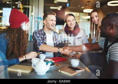 Junge Kerle Handshake unter ihre glückliche Freunde Stockfoto