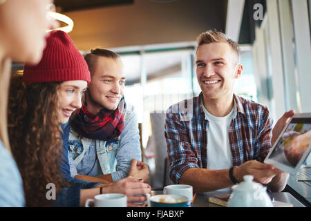 Freundlichen Teenager etwas im Internet beobachten, während der Rest im café Stockfoto