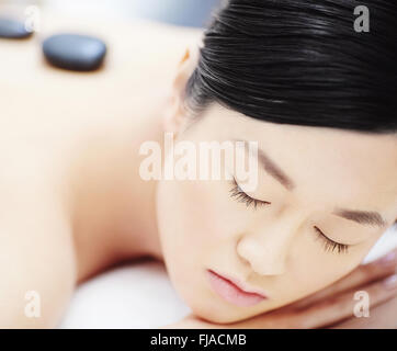Schöne asiatische Frau mit Stone-Massage im Wellness-salon Stockfoto