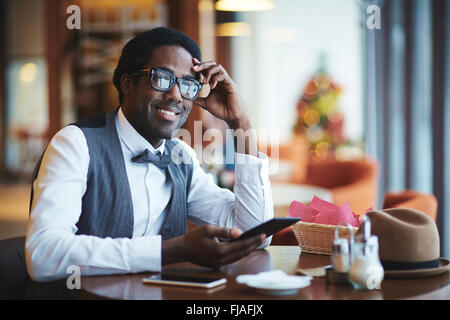 Eleganter junger Mann mit Smartphones im Café sitzen Stockfoto