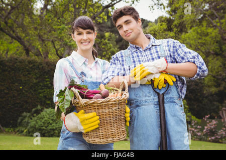 Junges Paar hält einen Korb mit frisch geernteten Gemüse Stockfoto