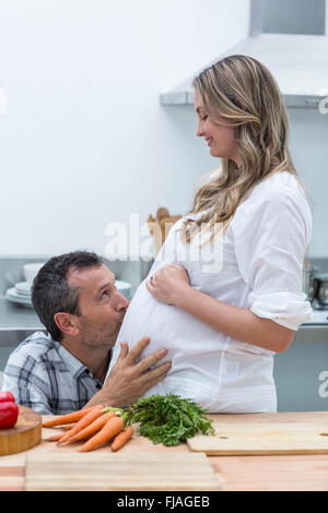 Mann den Bauch der schwangeren Frau küssen Stockfoto