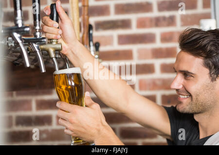 Gut aussehend Barkeeper einen Pint Bier in Strömen Stockfoto