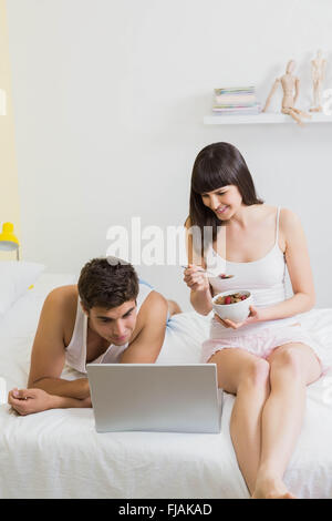 Junges Paar an Laptop auf dem Bett suchen Stockfoto