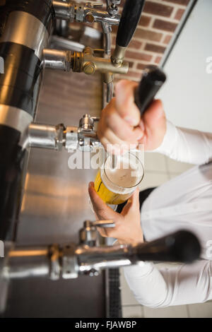 Gut aussehend Barkeeper einen Pint Bier in Strömen Stockfoto