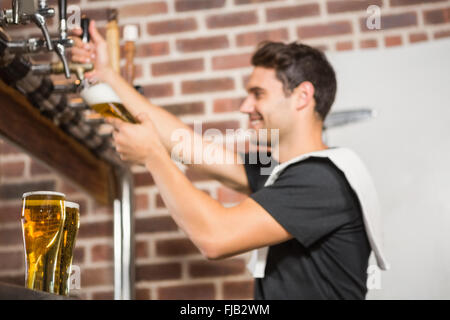 Gut aussehend Barkeeper einen Pint Bier in Strömen Stockfoto