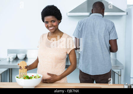 Schwangere Frau bereitet Salat in Küche Stockfoto