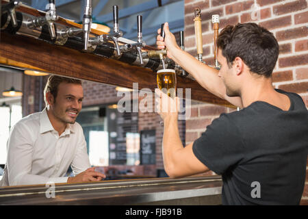 Gut aussehend Barkeeper gießen ein Bier für einen Kunden Stockfoto