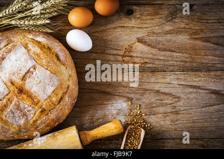 Backen Brot essen Hintergrund: frische Runde Laib Brot, frischen Eiern, Weizen, Ähren und Nudelholz auf hölzernen Hintergrund Stockfoto