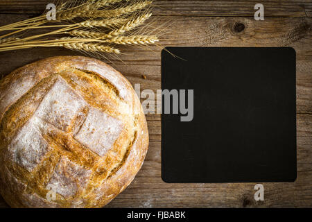 Tafel, Laib Brot und Weizen Ohren auf hölzernen Hintergrund, Draufsicht Stockfoto