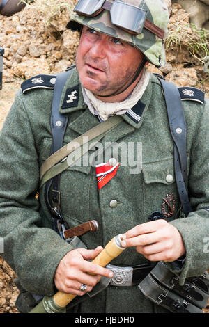 WW2re-enactment. Sie suchen bei der Deutschen Waffen-SS Storm Trooper im Graben der Fixierung eines stick Grenade, stielhandgranate. Iron Cross Band zu Brust gepinnt. Stockfoto