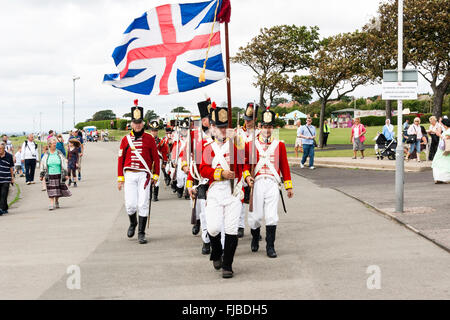 Napoleonische Kriege Re-enactment. Britischen Redcoats, 1 Fuß Regiment, Grenadier Guards, marschieren in Richtung Betrachter in einer Spalte mit Union Jack Flagge. Stockfoto