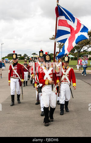 Napoleonische Kriege Re-enactment. Britischen Redcoats, 1 Fuß Regiment, Grenadier Guards, marschieren in Richtung Betrachter in einer Spalte mit Union Jack Flagge. Stockfoto