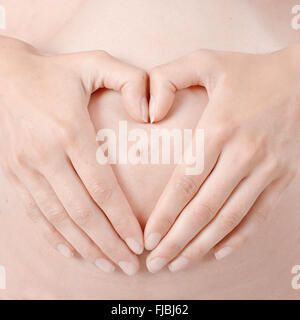 Schwangere Frau macht Herz Form Hände auf den Bauch. Stockfoto