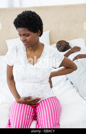 Schwangere Frau auf dem Bett sitzend Stockfoto