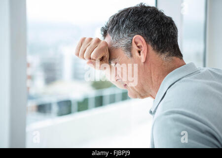 Gespannten Mann stützte sich auf Glasfenster Stockfoto