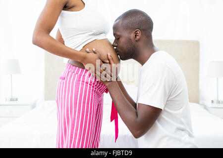 Mann küssen schwanger Womans Bauch im Schlafzimmer Stockfoto