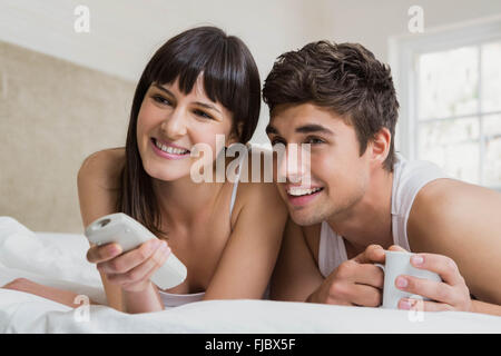 Junges Paar vor dem Fernseher zusammen auf Bett Stockfoto