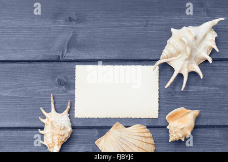 Die leere altes Foto und Muscheln liegen auf der blauen Schreibtisch aus Holz. Foto wird als Farbe Splash-Effekt bearbeitet. Stockfoto