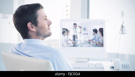 Zusammengesetztes Bild des lächelnden Geschäftsmann sitzt an seinem Schreibtisch Stockfoto