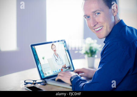 Zusammengesetztes Bild des lächelnden Geschäftsmann mit Laptop im Büro Stockfoto
