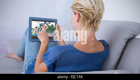 Zusammengesetztes Bild blonde Frau mit ihrem Tablet auf der couch Stockfoto
