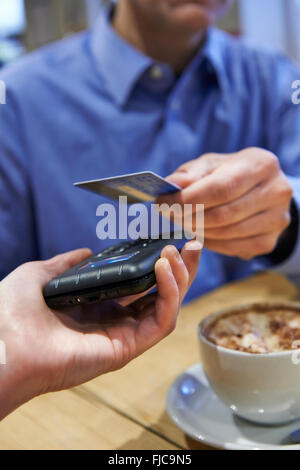 Kunden mit kontaktloses Bezahlen In Coffee-Shop Stockfoto