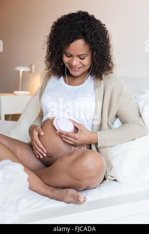 Schwangere Frau mit einem fetal Doppler zu Hause Stockfoto