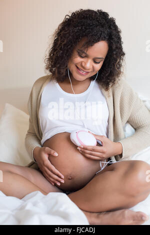 Schwangere Frau mit einem fetal Doppler zu Hause Stockfoto