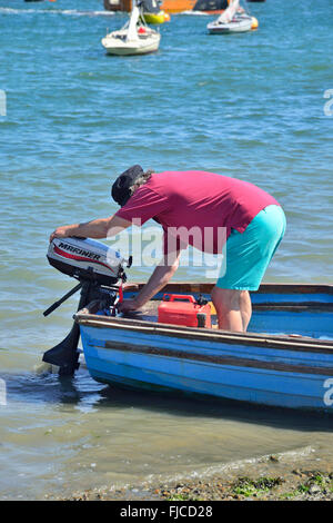 Mann einstellen Außenbordmotor auf Tender auf Itchenor Hart/Helling, Chichester, West Sussex, England, Großbritannien Stockfoto