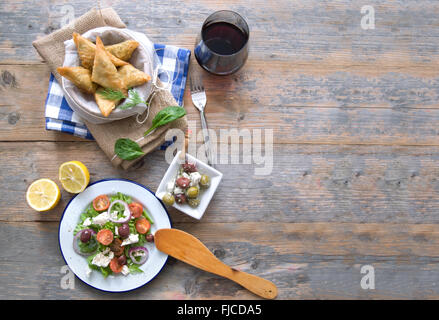 Feta-Käse und Spinat Blätterteig-Gebäck und griechischer Salat auf einem Holztisch gelegt Stockfoto