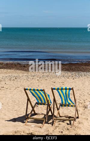 Zwei blau-weiß gestreiften Strandkörbe am Sandstrand mit dem Rücken zur Kamera Stockfoto